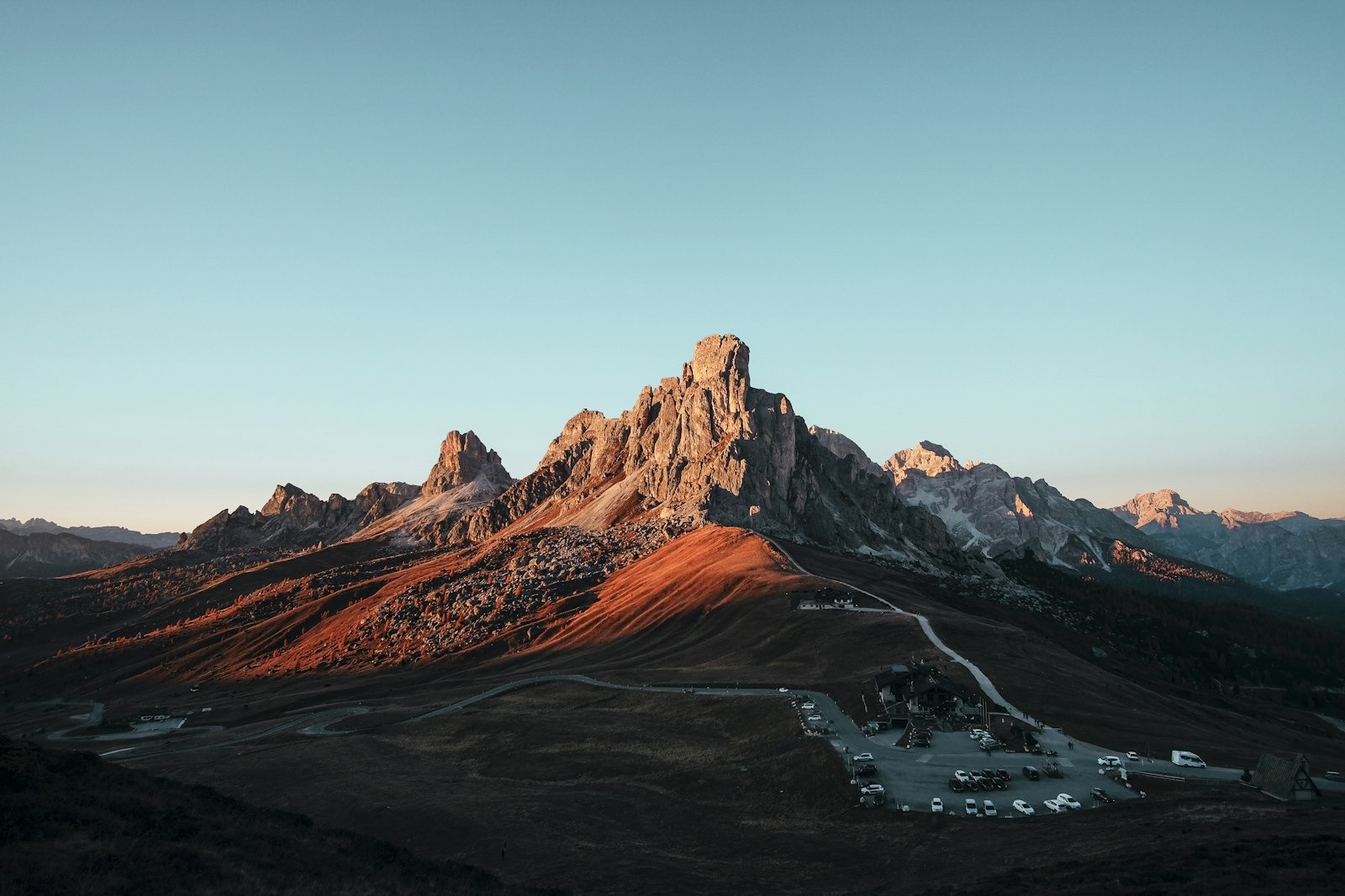 Golden sunset over a calm alpine lake below dark peaks
