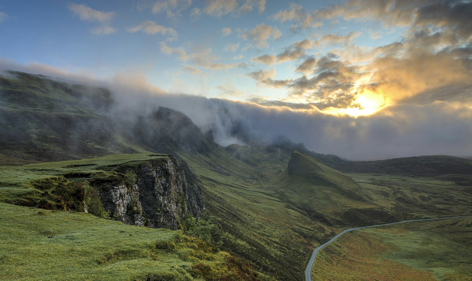 Morning mist drifting through a green valley below the ranges