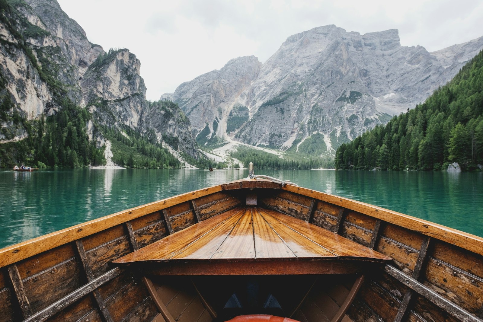 Rowboats on a turquoise alpine lake beneath dramatic rocky cliffs