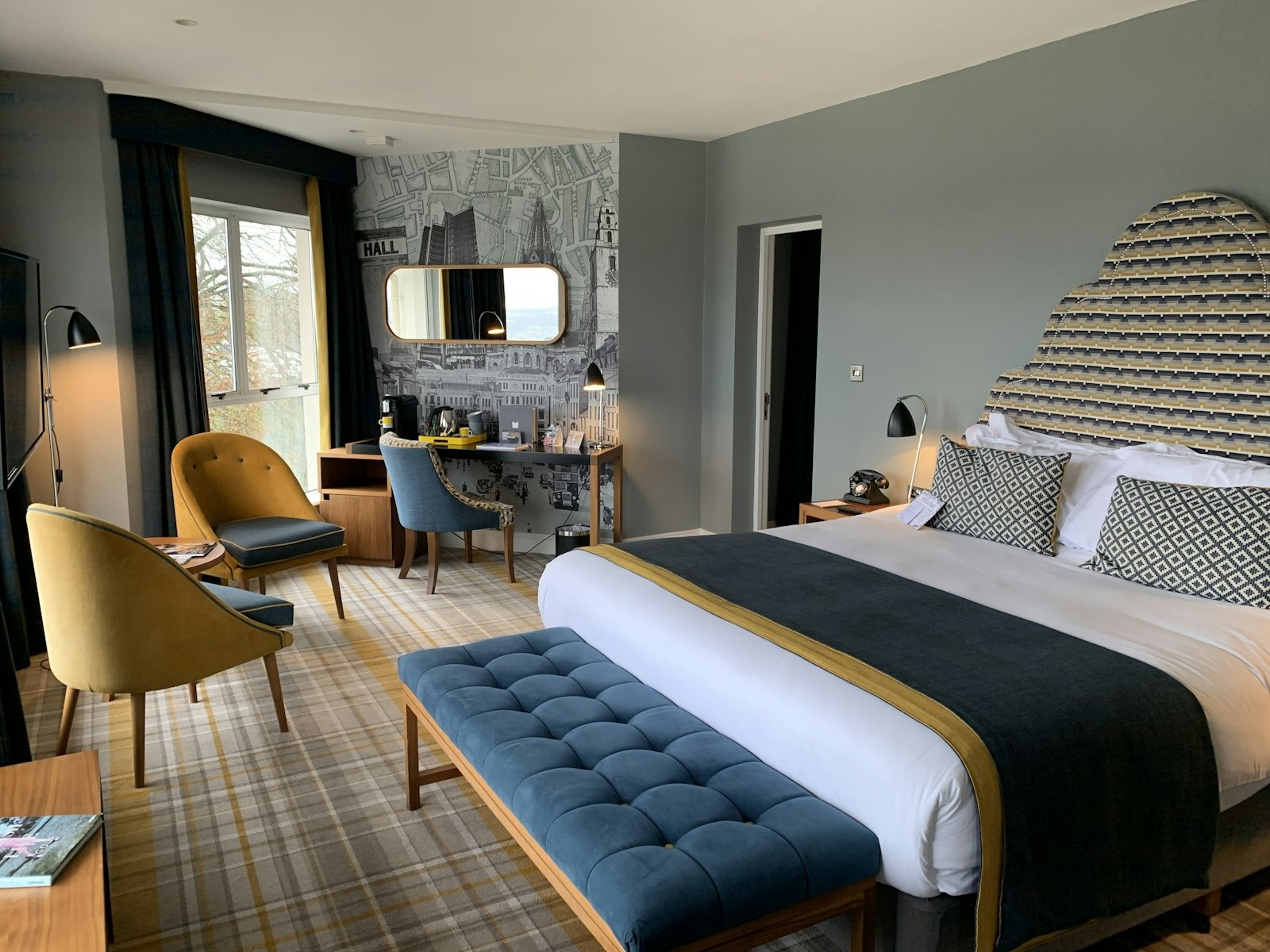 Junior suite — mustard and teal armchairs, king bed and map wallpaper
